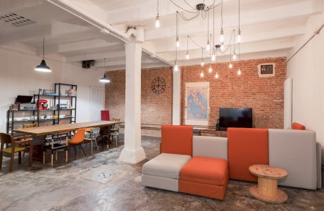 A modern loft space with exposed brick walls, pendant lighting, and a mix of furniture styles.