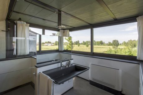 A modern bathroom with large windows offering a scenic rural view, featuring sleek fixtures.