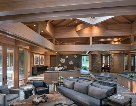 Spacious open-plan living area with exposed wooden beams, stone fireplace, and modern furnishings.