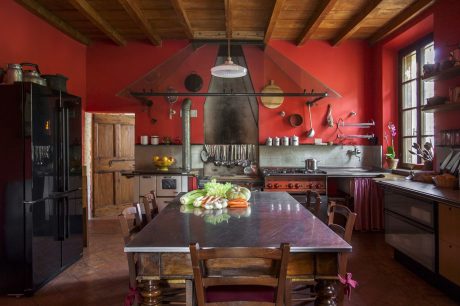 Rustic kitchen with exposed beams, red walls, and wooden furniture creates cozy atmosphere.