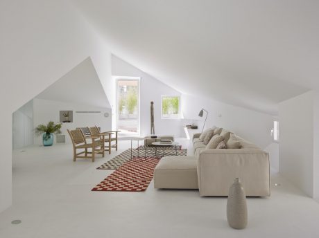 Cozy attic living space with angled ceilings, large windows, and modern furnishings.