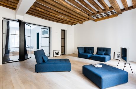 Rustic wooden ceiling beams contrast with modern furniture and large windows in this chic space.