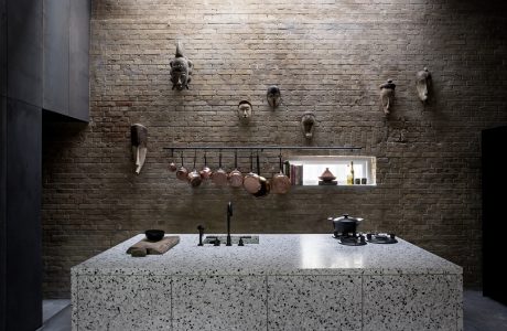 Rustic brick wall with assorted decor and cooking equipment on a sleek granite counter.