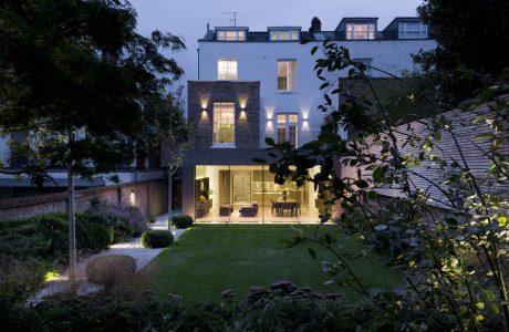 A multi-story residential building with a well-lit outdoor garden and paved walkway.