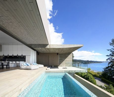 Striking concrete architecture with a sleek, modern pool overlooking a scenic lake.