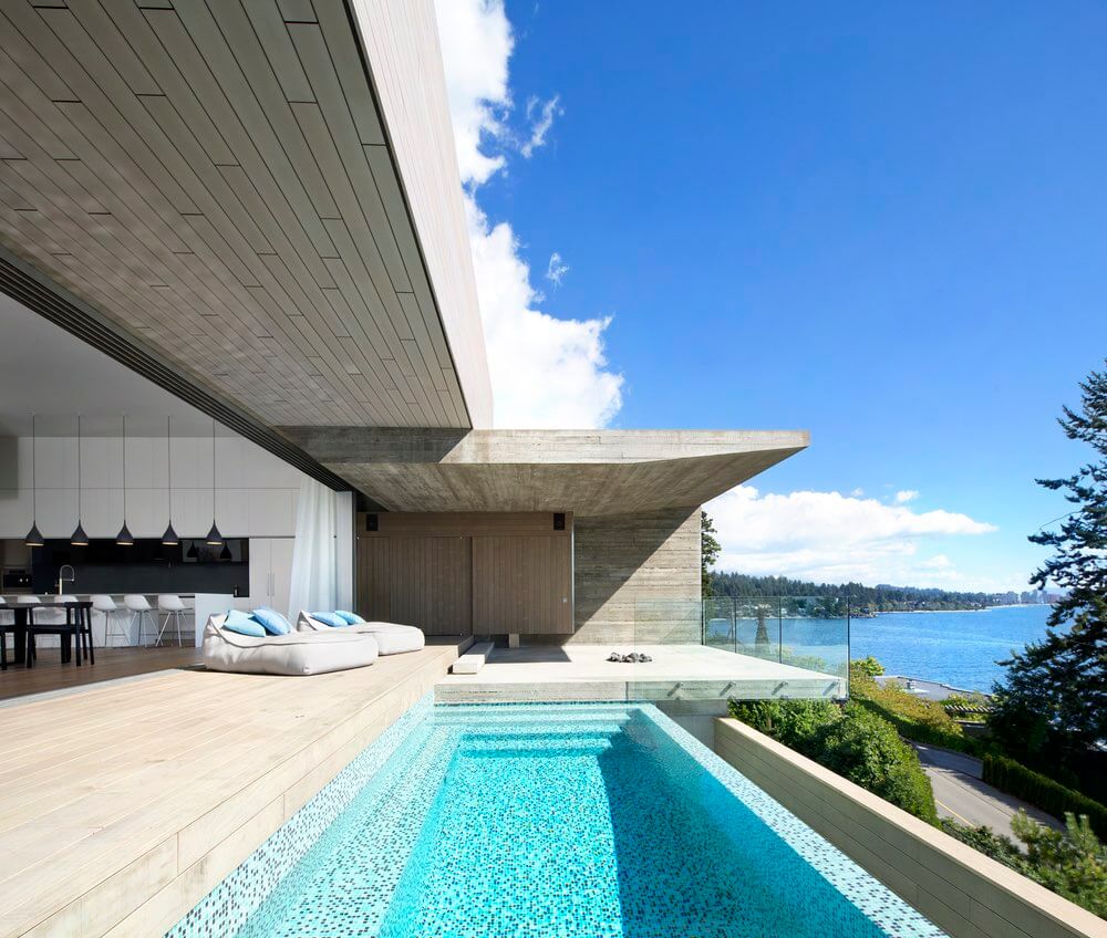 Striking concrete architecture with a sleek, modern pool overlooking a scenic lake.