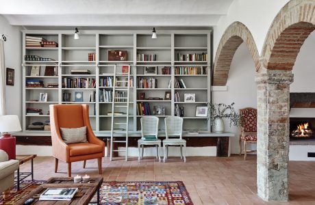 Spacious living room with large built-in bookshelves, brick arches, and a cozy fireplace.