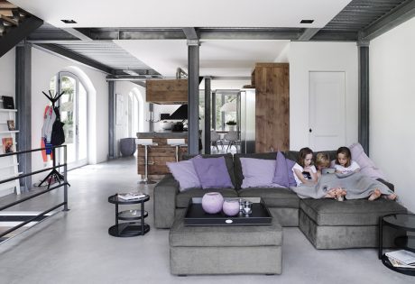 Spacious, open-concept living area with rustic wood accents, modern gray furniture, and a cozy seating arrangement.