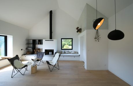 An airy, minimalist living space with a fireplace, built-in shelving, and modern lighting fixtures.