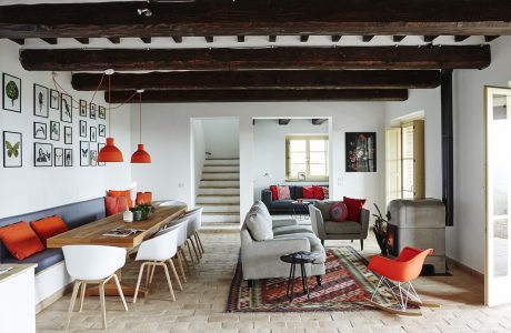 Rustic wooden beams, modern furnishings, and vibrant pops of color create a cozy, eclectic living space.