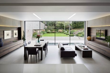 Modern, open-plan living area with large windows overlooking a lush garden. Sleek, minimalist decor.