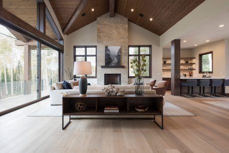 Spacious living room with vaulted ceiling, wood beams, and large windows overlooking natural scenery.