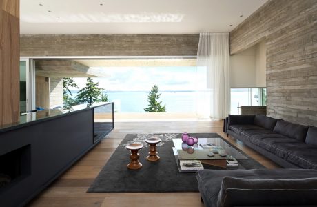 Minimalist living space with rustic concrete walls, expansive windows, and modern furnishings.