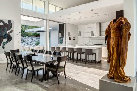 Sleek, modern kitchen and dining room with large windows, abstract artwork, and a sculptural bronze statue.