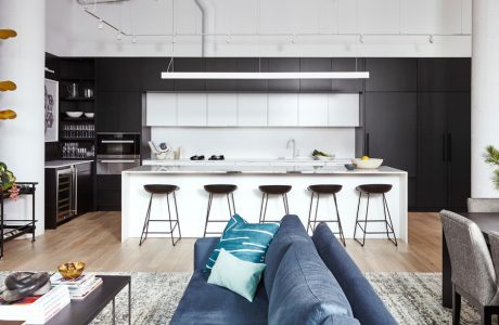 Sleek, modern kitchen with black cabinetry, white island, and floating wood shelves.