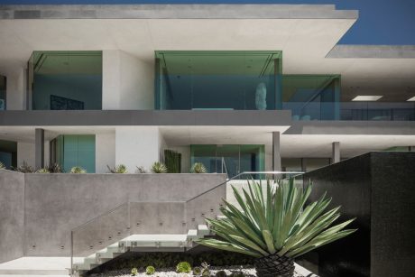 Sleek, modern architecture with clean lines, glass panels, and lush landscaping.