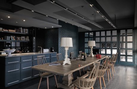 Spacious open-concept kitchen and dining area with dark cabinetry, exposed brick, and wooden furnishings.