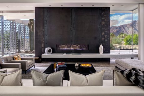 Modern living room with large fireplace, minimalist furniture, and scenic mountain view.