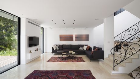 Spacious, modern living room with sleek furniture, artwork, and decorative staircase.