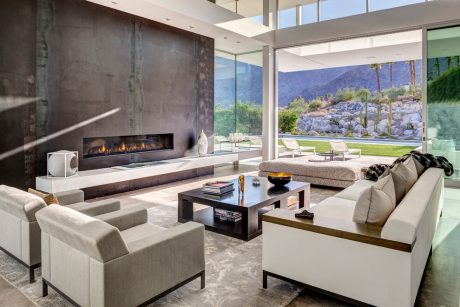 Luxurious modern living room with fireplace, floor-to-ceiling windows, and minimalist furnishings.