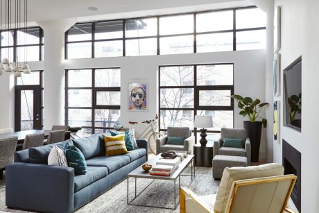 Spacious living room with large windows, modern furnishings, and abstract artwork.