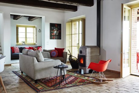 A cozy living room with exposed beams, a fireplace, and a mix of modern and rustic decor elements.