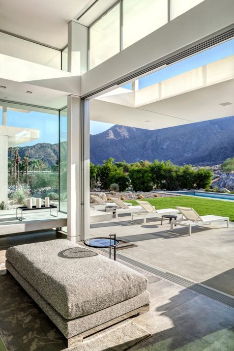 Striking modern architecture with sleek glass walls framing lush mountain view.