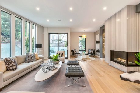 Spacious modern living room with floor-to-ceiling windows, sleek furniture, and a fireplace.