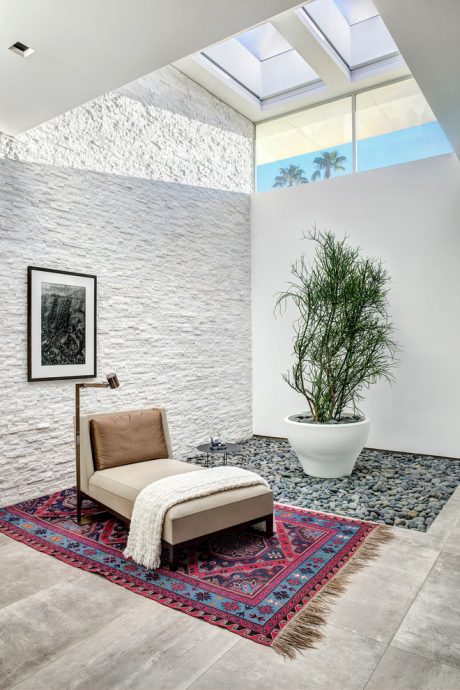 Modern interior with stone wall, skylights, potted plant, and patterned rug.