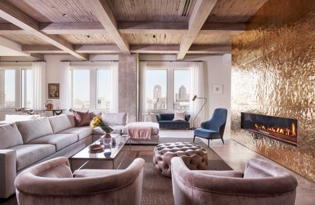 Spacious loft with exposed wooden beams, sleek furniture, and a stunning fireplace.