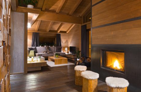 Cozy mountain lodge interior with wood beams, fireplace, and rustic furniture.