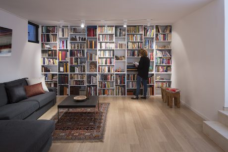 A cozy living room with built-in bookshelves covering an entire wall, holding a vast collection of books.