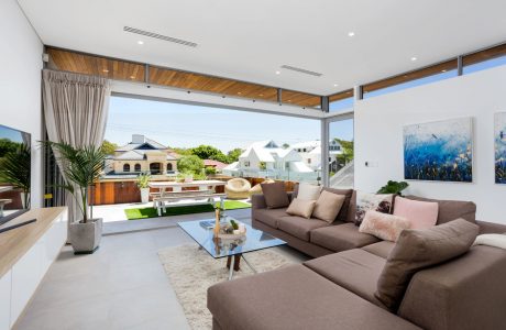 Large open-concept living room with floor-to-ceiling windows, wooden beams, and modern furniture.