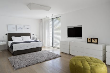 Spacious modern bedroom with clean lines, neutral colors, and a cozy seating area.