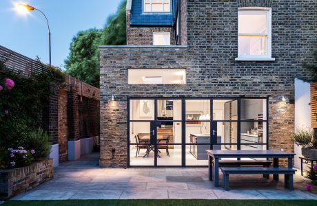 A modern, brick townhouse with large windows, an open floor plan, and outdoor seating area.