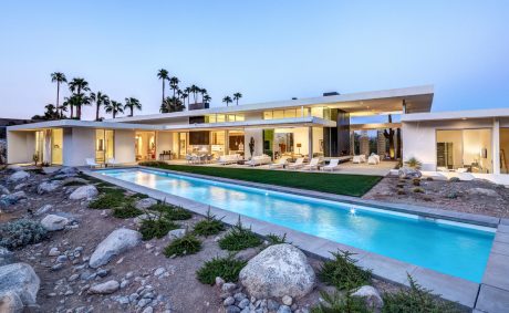 Sleek, modern architecture with large glass windows, outdoor pool, and lush landscaping.