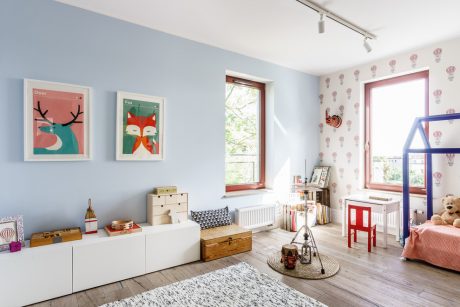 Bright, airy children's room with colorful artwork, shelving, and playful furnishings.