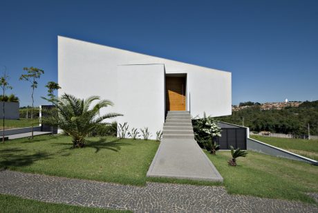 Modern, minimalist architecture with clean lines, contrasting textures, and lush landscaping.