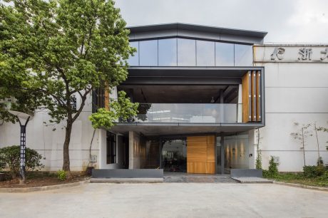 A modern, glass and wood building with a prominent roofline, surrounded by trees.