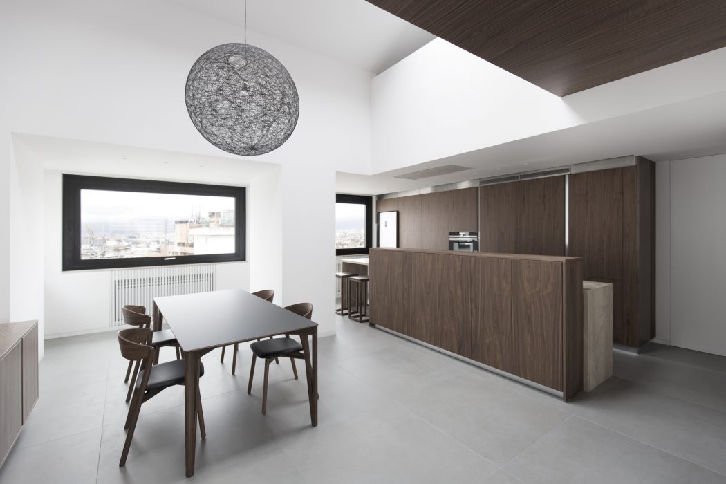 Contemporary open-plan kitchen and dining area with minimalist decor and large window.