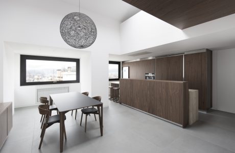 Contemporary open-plan kitchen and dining area with minimalist decor and large window.