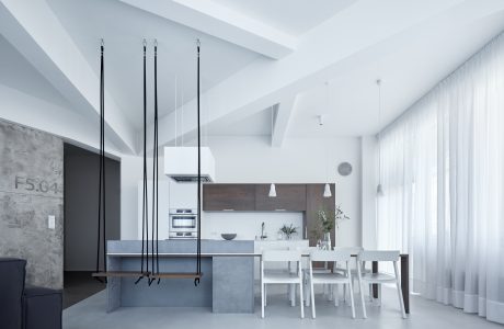 Minimalist kitchen and dining area with concrete accents, pendant lights, and modern furnishings.