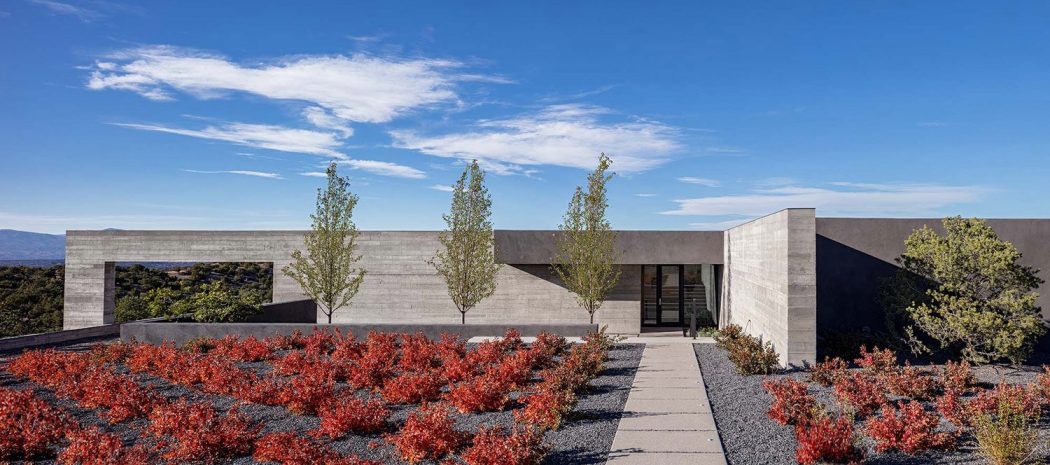 A sleek modern building with a bold concrete facade and a lush landscaped courtyard.