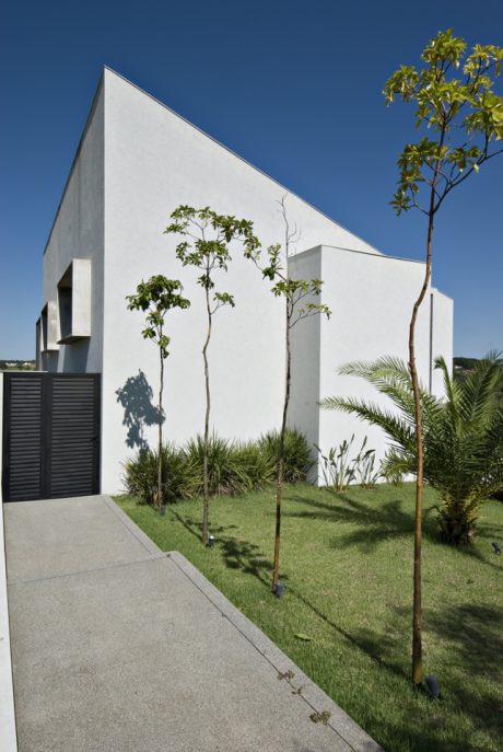 Modern, minimalist architecture with native vegetation and a paved walkway leading to the entrance.