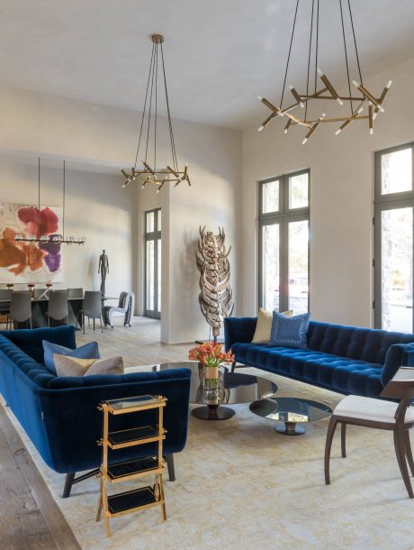 Spacious living room with modern lighting fixtures, plush blue sofas, and unique wall decor.