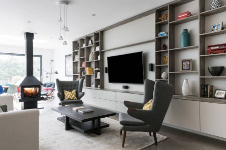 Stylish living room with built-in shelving, modern furniture, and a large TV display.