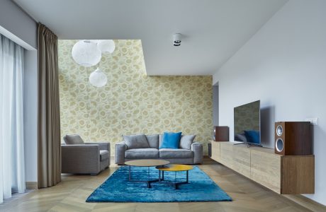 Spacious living room with modern furnishings, patterned wall, and pendant lighting.