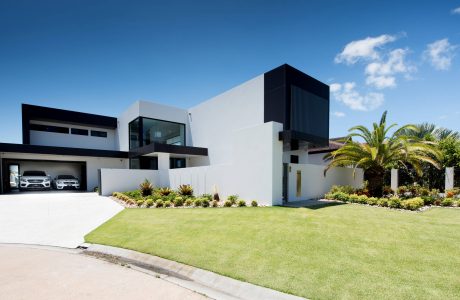 Sleek, modern architecture with clean lines, garage doors, and lush landscaping.