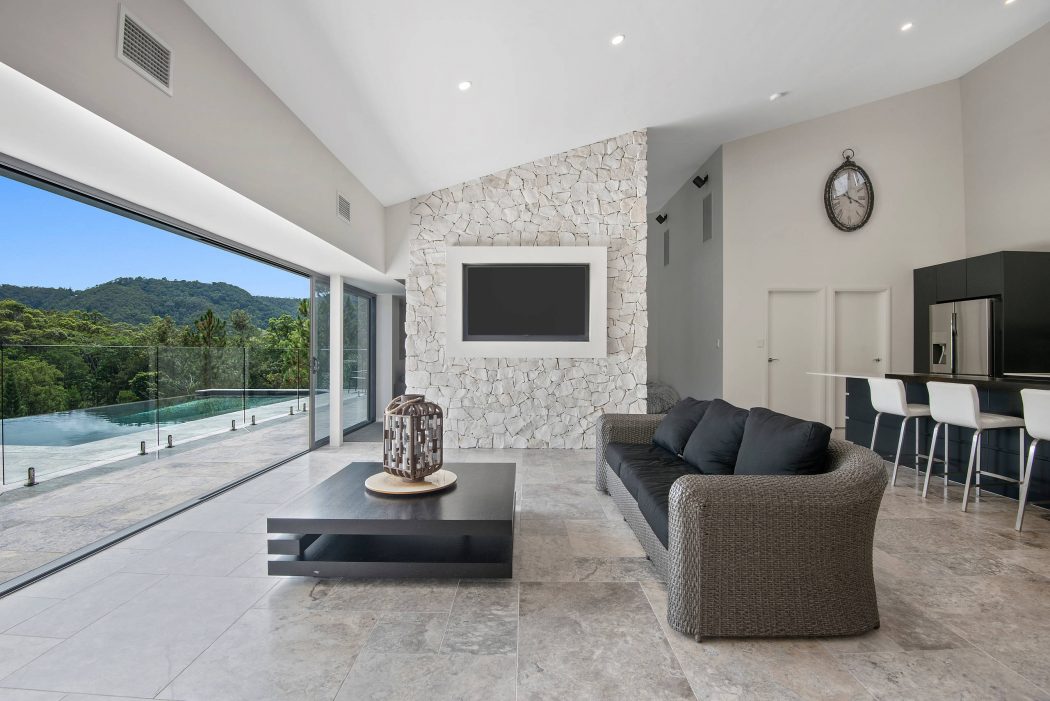 Spacious living room with sleek stone wall, recessed lighting, and panoramic glass doors.
