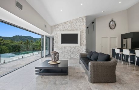 Spacious living room with sleek stone wall, recessed lighting, and panoramic glass doors.